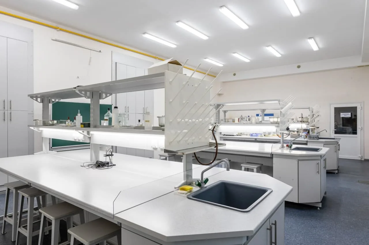 Лаборатория с островными столами, вытяжными шкафами и мойками.